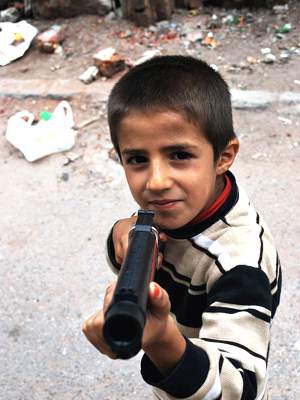 Young boy with toy gun, smiling, pointing it at camera